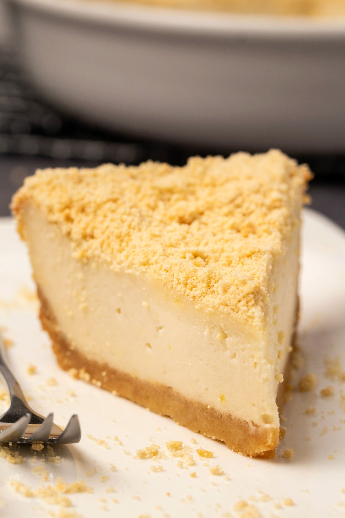 Slice of vegan baked cheesecake on a white plate with a cake fork. 