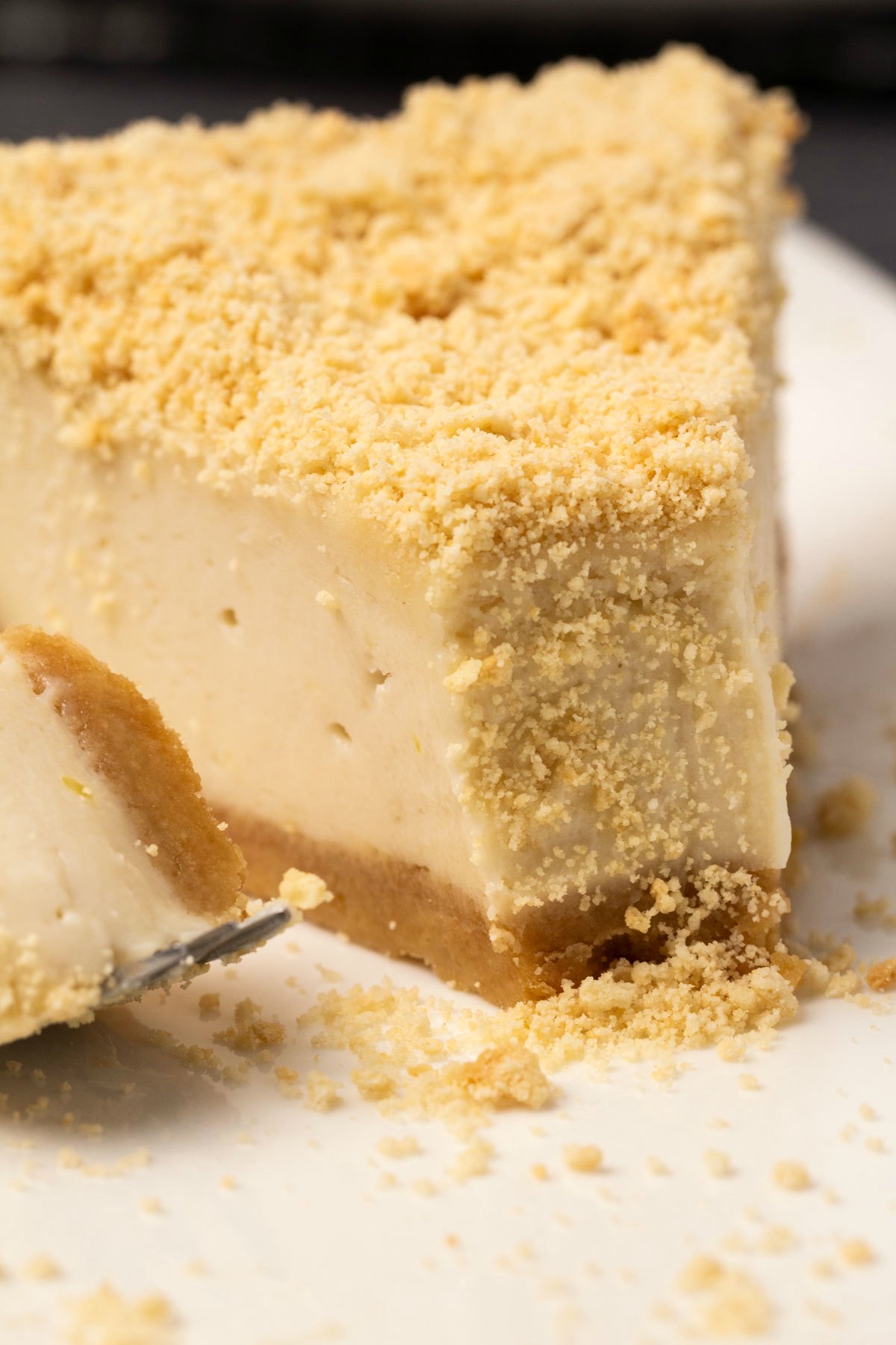 Slice of dairy free baked cheesecake on a white plate with a cake fork. 