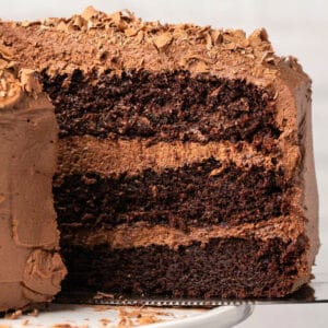 Dairy free chocolate cake on a white cake stand.