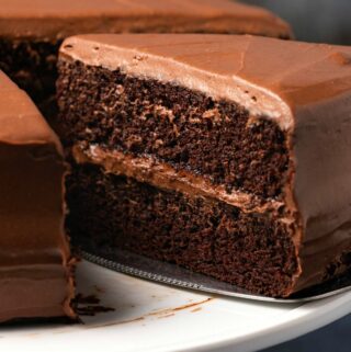 Vegan gluten free chocolate cake on a white cake stand.