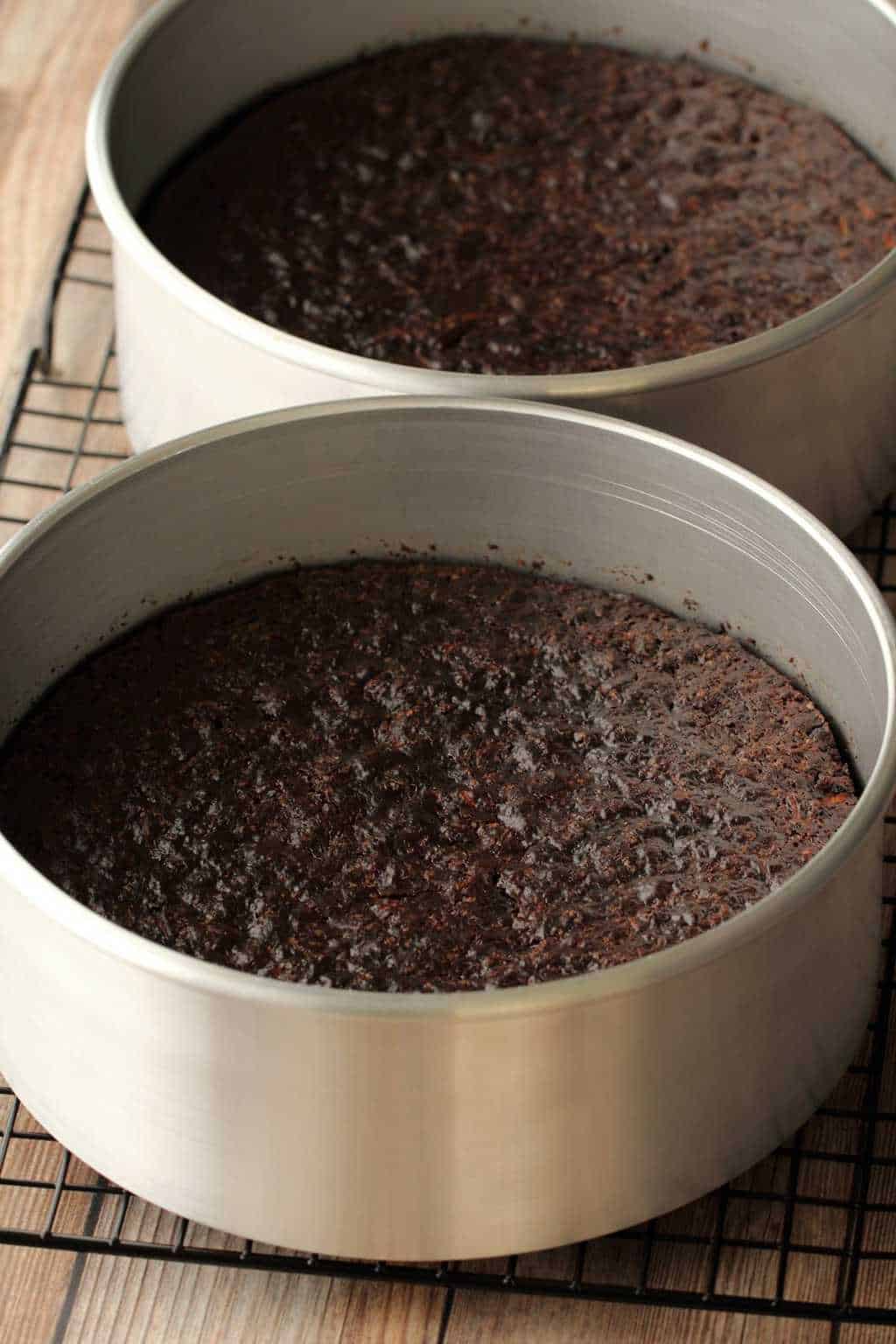 Vegan chocolate zucchini cake straight from the oven, in cake pans on a wire cooling rack. 