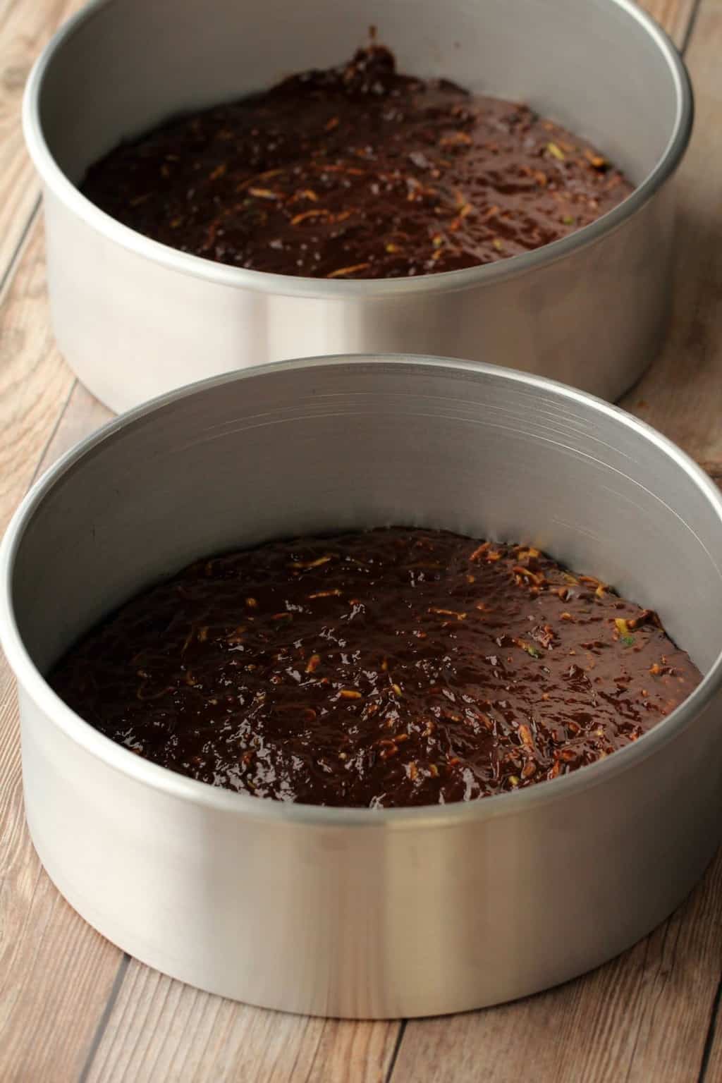 chocolate zucchini cake batter in two cake pans ready to go into the oven. 