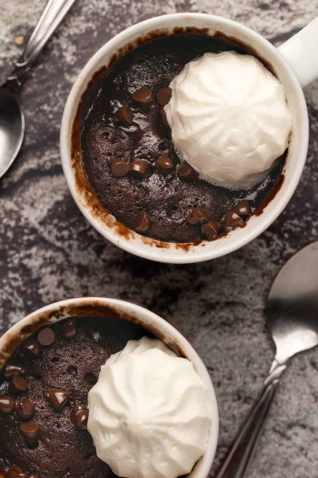 Vegan mug cake topped with vegan cream and chocolate chips. 