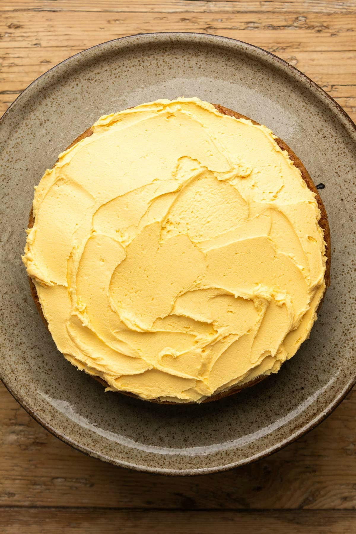 Frosting an orange cake on a cake stand.