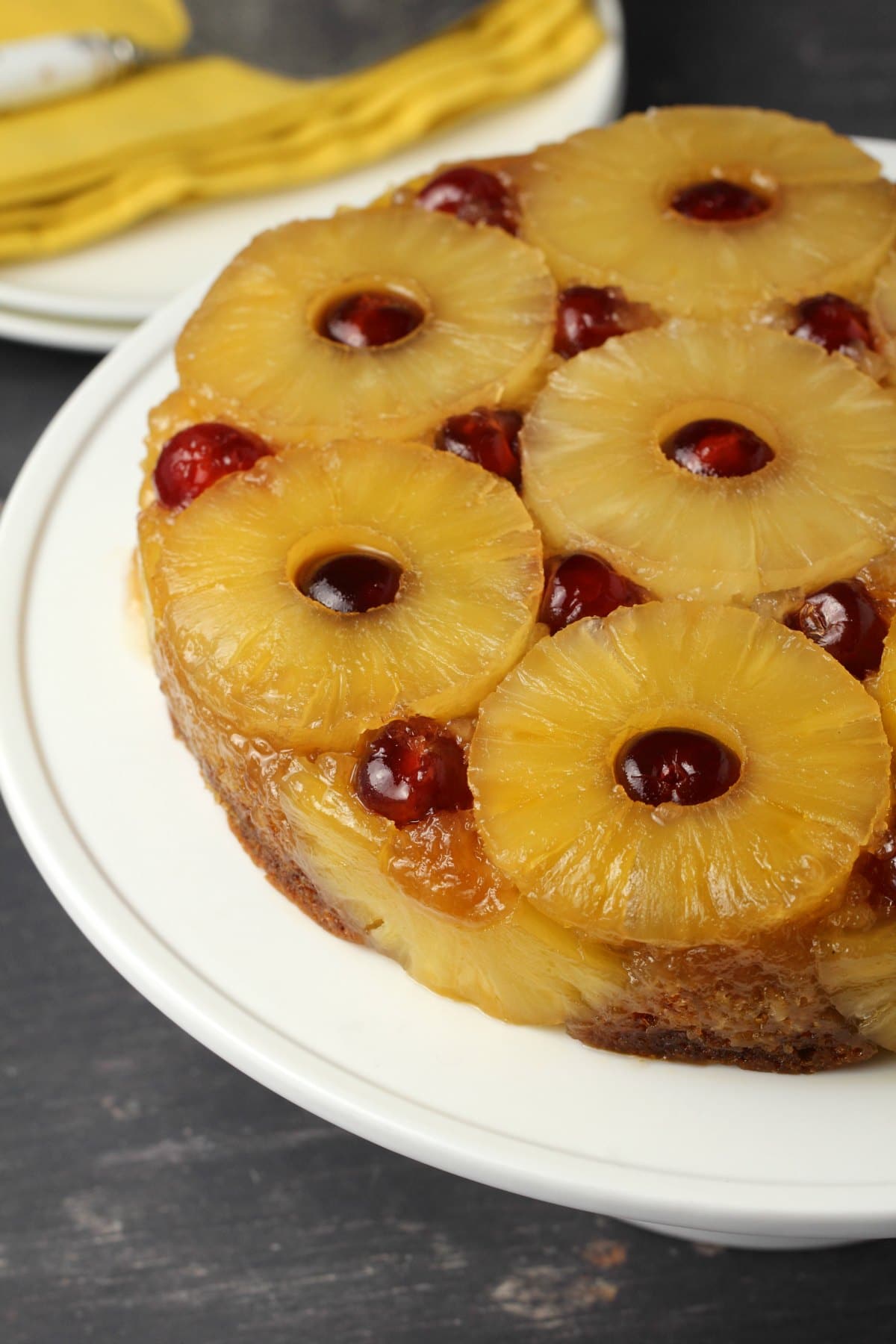 Vegan pineapple upside down cake on a white cake stand. 