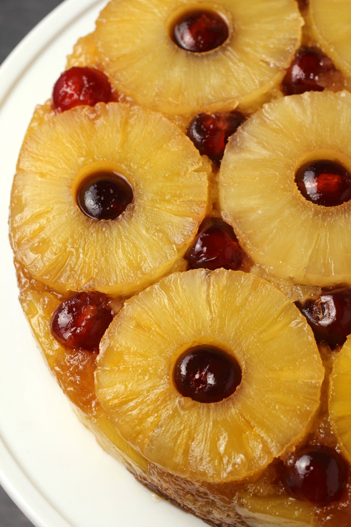 Vegan pineapple upside down cake on a white cake stand. 