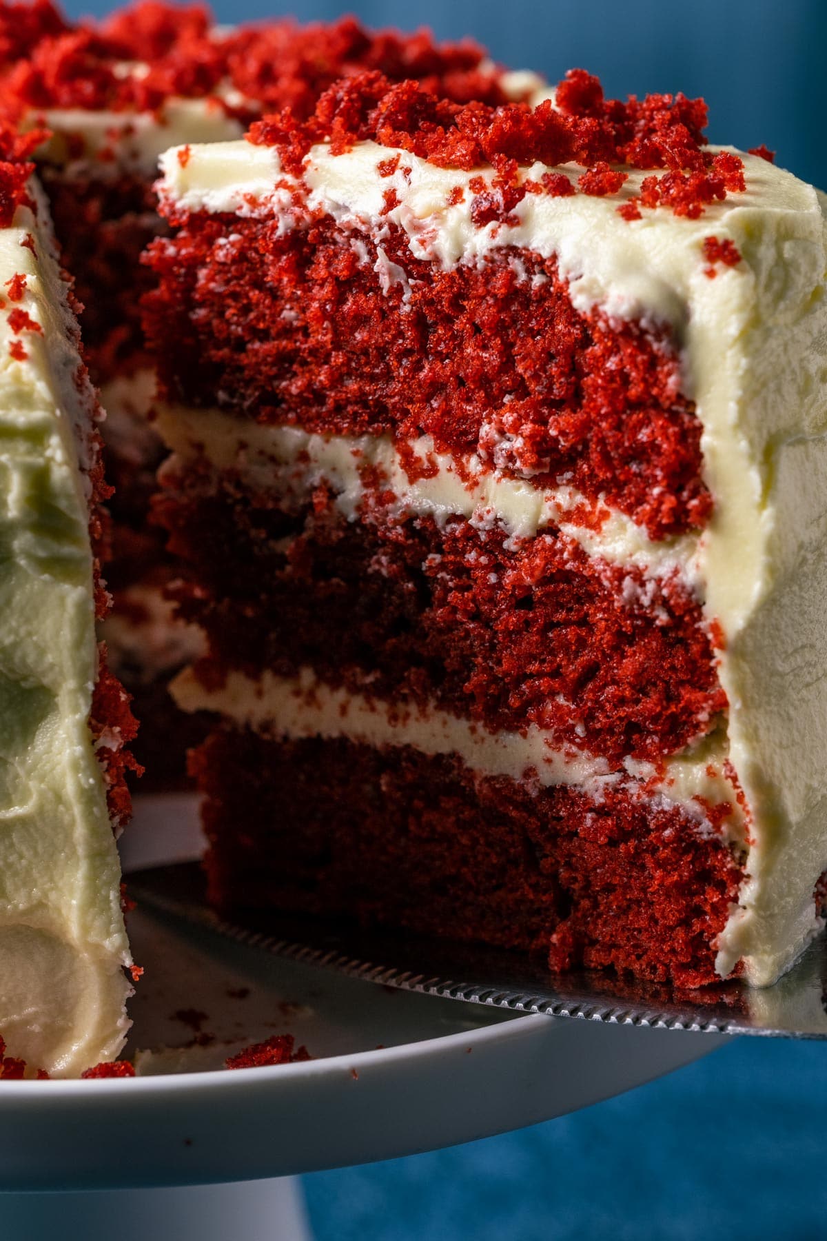 Slice of vegan red velvet cake on a cake lifter.