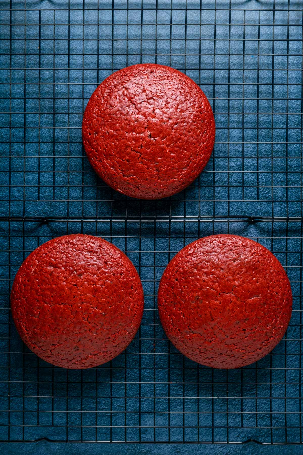 Vegan red velvet cake layers cooling on a wire cooling rack.