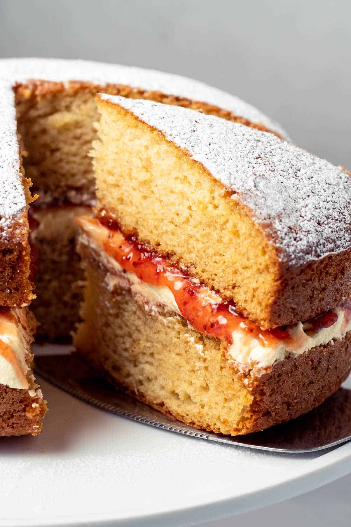 Victoria sponge cake on a white cake stand.