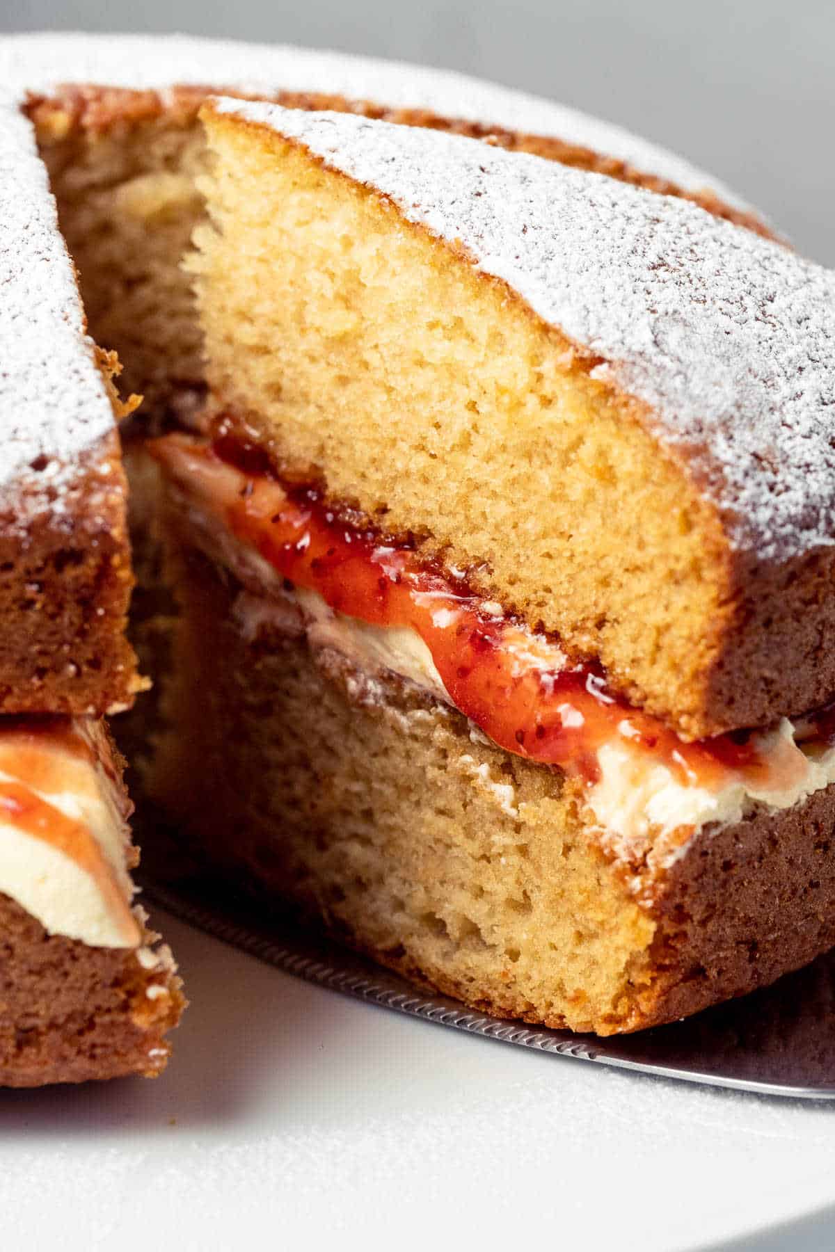 Cake with one slice cut on a white cake stand.