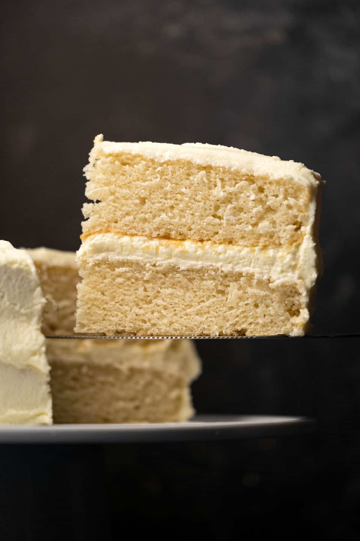 Slice of vegan white cake on a cake lifter. 